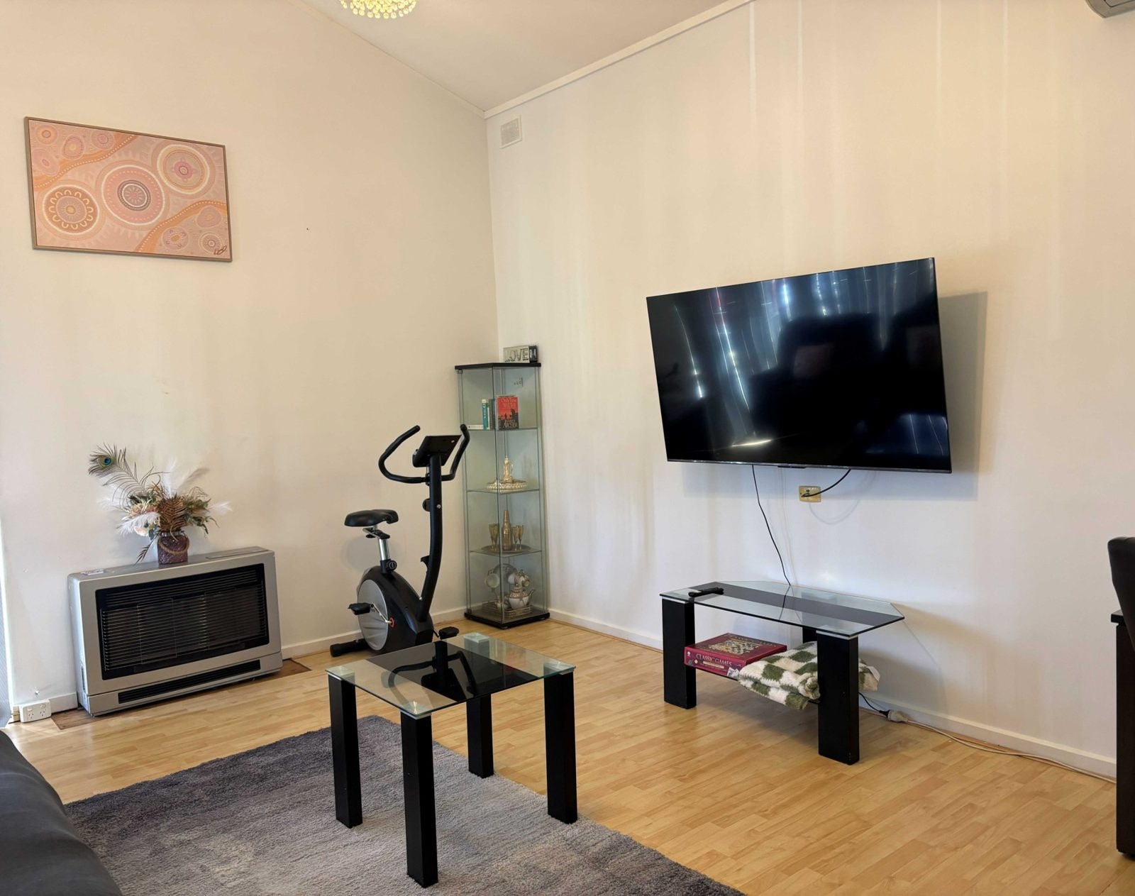 Open living area of a CISP SIL home with wall-mounted TV and exercise bike